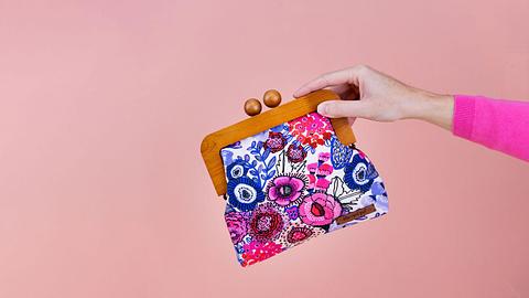 holding pink and purple floral wooden clutch purse